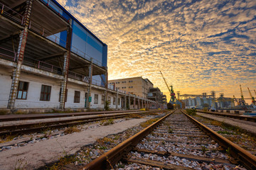 Fototapeta premium The territory of an old factory with railroad tracks at sunset