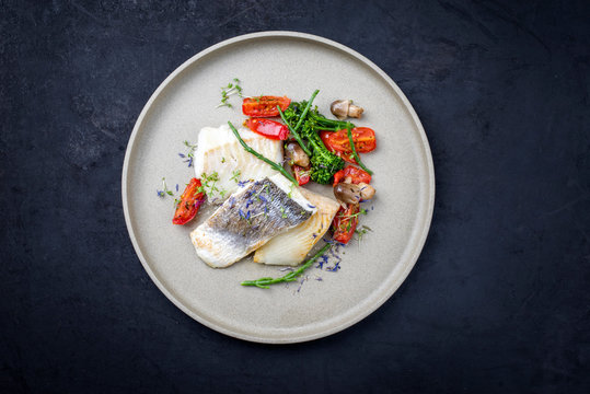 Gebratenes italienisches Kabeljau Fisch Filet mit Brokkoli, Queller und Tomaten als Draufsicht auf einem Modern Design Teller mit Textfreiraum