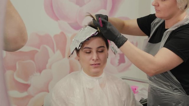 Professional hairdresser woman washes hair dye girl.