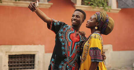African young happy and good looking man and woman in traditional clothes standing together outdoor...