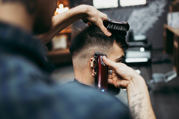 Good looking young adult man getting a hair and beard styling and dressing treatment by professional hairstylist.