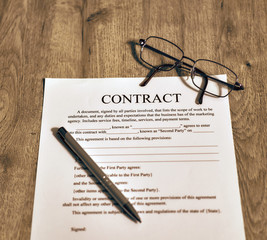 On the wooden table is the contract template. Sunglasses