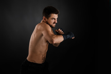 Fototapeta na wymiar Sportsman boxer throwing a fierce and powerful punch. muscular man on black background.