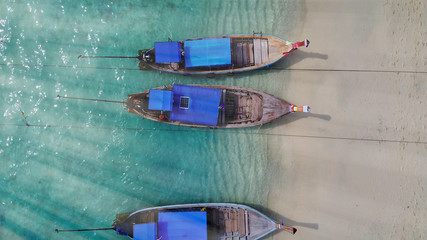 Top view or aerial view of beautiful crystal clear water and white beach with long tail boats in summer of tropical island