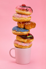 Colorful donuts breakfast composition with different color styles of donuts and fresh coffee on pink background
