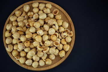 Hazelnut nut or noisettes nuts group Protein and healthy food for diet in a wooden plate on a black background.