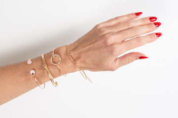 woman arm hand with jewelry on white background in top view and red nails