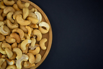 Cashews Nut or cashewkerne nuts group Protein and healthy food for diet in a wooden plate on a black background.