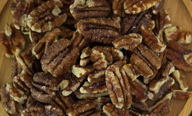 pecan nut or Pekannuss nuts group Protein and healthy food for diet in a wooden plate on a black background.