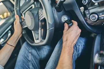 Male hand holding a steering wheel before purchasing a new automobile in showroom.