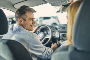 Smiling man and cheerful girl having fun and getting ready to drive on new car. Business concept.