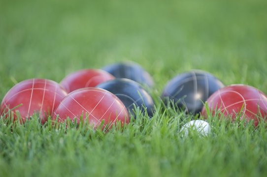 Picture of colourful bocce balls on the lawn under the sunlight with a blurry background