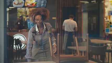 Portrait of african waitress cleaning closed restaurant after working day,