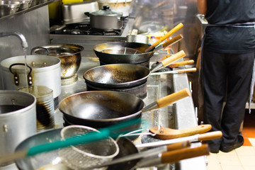 Chefs at work in a commercial kitchen. Male chef cooking using wok styled pans in a takeaway / restaurant setting