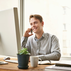 Businessman smiling while talking on the phone at work