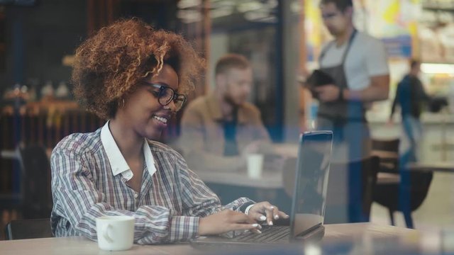 Attractive afro businesswoman working on laptop in cafe during break