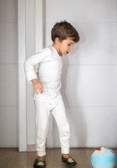 Small kid playing with ball in a hallway.