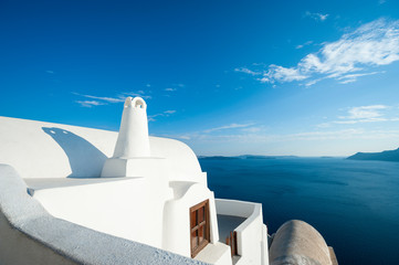 Bright abstract view of whitewashed Greek island architecture with calm blue Mediterranean Sea horizon in Santorini, Greece