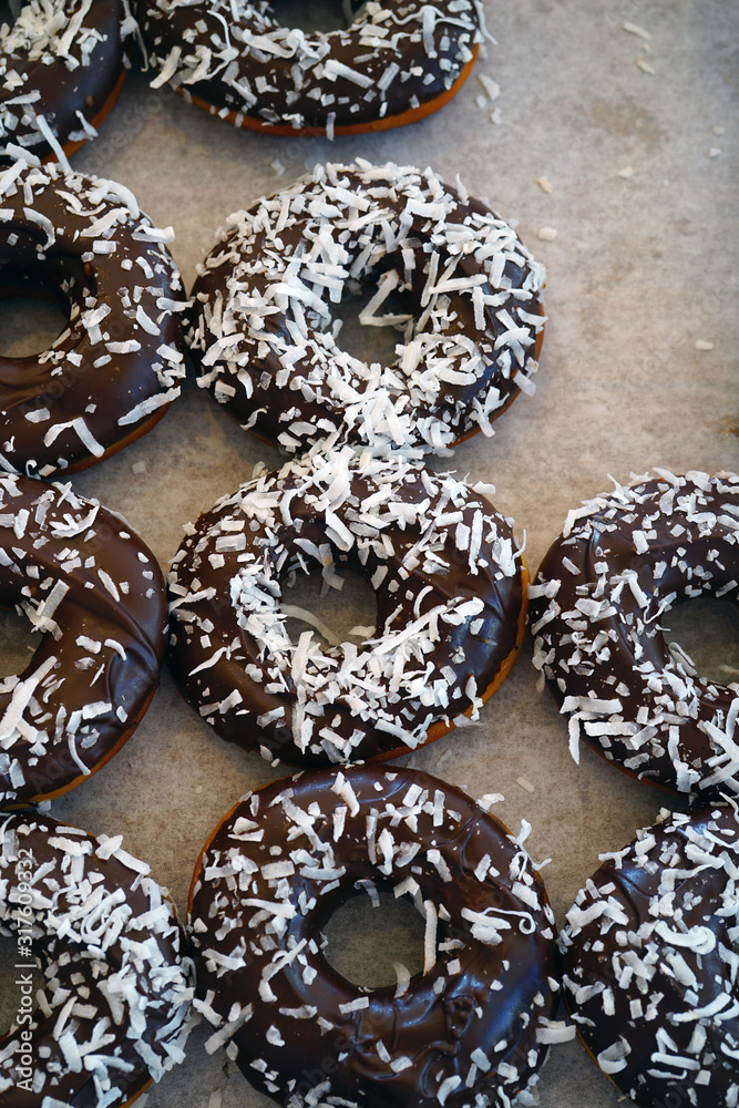 Wall mural Fresh donuts with chocolate icing and coconut flakes