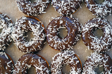 Fresh donuts with chocolate icing and coconut flakes