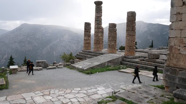 Delphi, Grece, Europe - dicember 30 2019: turists visit the ruins of the ancient temple of Apollo, archaeological site of Delphi along the slope of Mount Parnassus, UNESCO World Heritage, Greece.