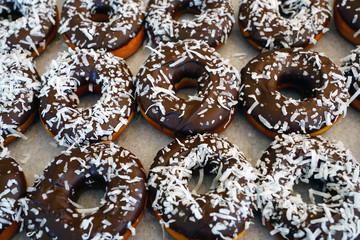 Fresh donuts with chocolate icing and coconut flakes