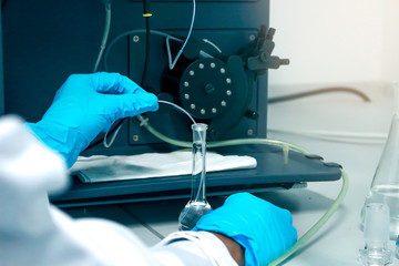 Research scientist hand with blue chemical protective gloves using volumetric flask for doing...
