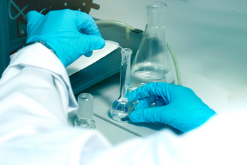 Research scientist hand with blue chemical protective gloves using volumetric flask for doing experiment to determine the levels of heavy metals in solutions by ICP (Inductively Coupled Plasma spectro