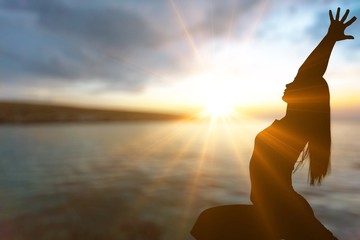 Woman yoga silhouette meditating at sunset