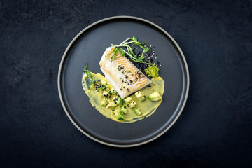 Gebratenes Kabeljau Fisch Filet mit Kaviar, Avocado Scheiben und Mango Senf Creme als Draufsicht...