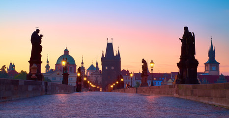Fototapeta premium Prague at night, panoramic image. Charles Bridge early in the morning with unrecognizable tourists and town guests waiting on the famous bridge for the sunrise