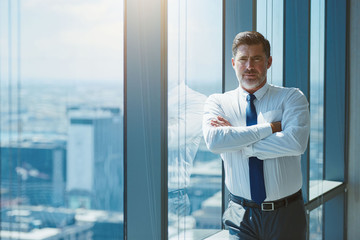 Fototapeta premium Mature businessman with arms crossed looking serious and confident