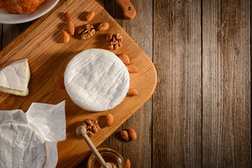 Camembert cheese, almond, walnuts and honey on wooden background