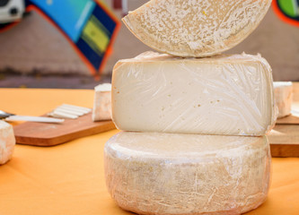 Some whole and cut cheese  for saling on the table at the market stall. Healthy food concept.