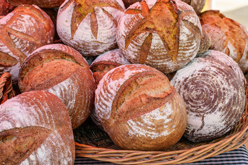 Big wicker basket ful of fresh baked homemade loafs of bread at the market for sale.