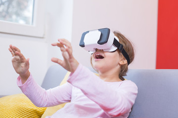 young girl using virtual reality goggles at home