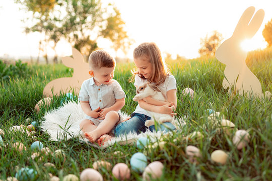 Little boy and girl play with the rabbit. happy little girl holding cute fluffy Bunny. Spring photo with beautiful young girl and boy with their Bunny.