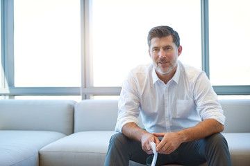 Mature businessman on couch looking thoughtful with paperwork