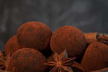 Craft chocolate truffles on plate with cocoa powder and anise, cinnamon, cardamom.