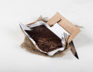 Bitter dark chocolate on a wrapper on a light background