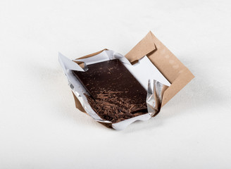 Bitter dark chocolate on a wrapper on a light background