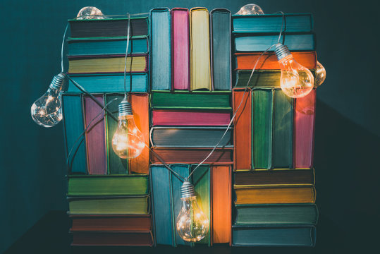 Colorful fairy books with light bulbs illumination on blue background