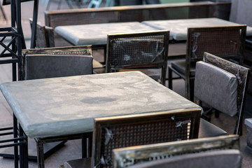 Fototapeta na wymiar street cafe with a gray painted iron table and black iron chairs with soft pillows in a rough urban style, nobody close up.