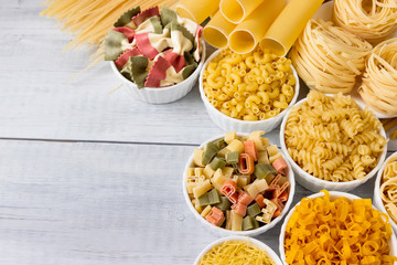 Different of types and shapes of dry Italian  of pasta on a wooden table.