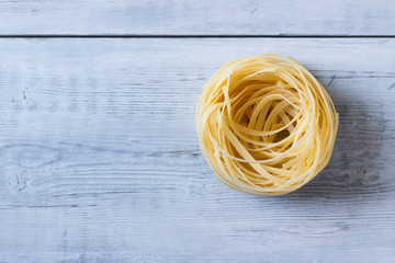 Raw  Fettuccine(nest) pasta  on  rustic background with copy space.