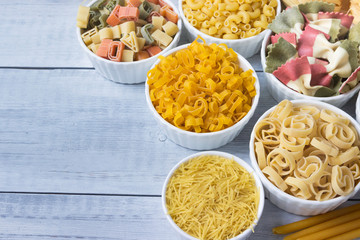 Different of types and shapes of dry Italian  of pasta on a wooden table.