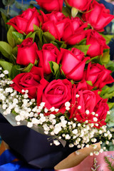 A bouquet of red roses with white little flowers