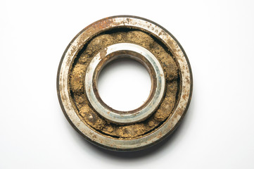 Old and rusty iron ball bearing on white background. Front view. The gap between the balls and the base is clogged with dust, sand and dirt. The concept of timely cleaning of bearings.