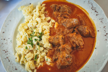 Traditional hungarian and austrian dish - beef goulash with garnish egg noodles, mashed potatoes in Vienna, Austria