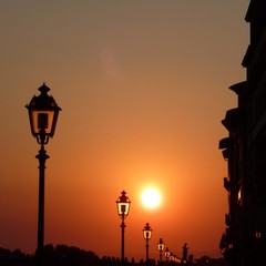 Sunset in Florence, Italy. A line of street lamps and the silhouette of the buildings overlooking the Arno river
